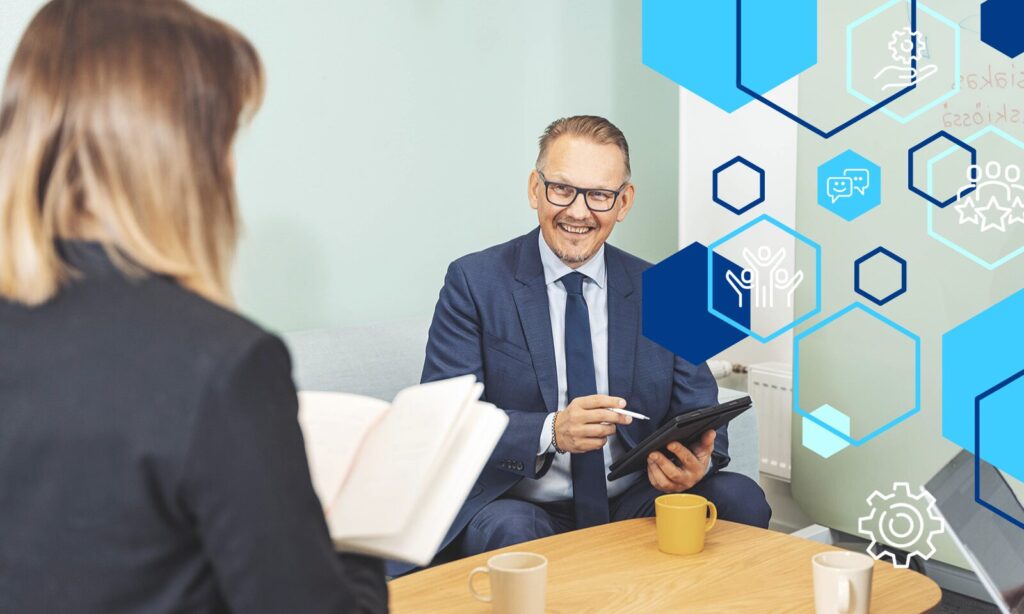 Henkilöt keskustelemassa toimiston pöydän äärellä.