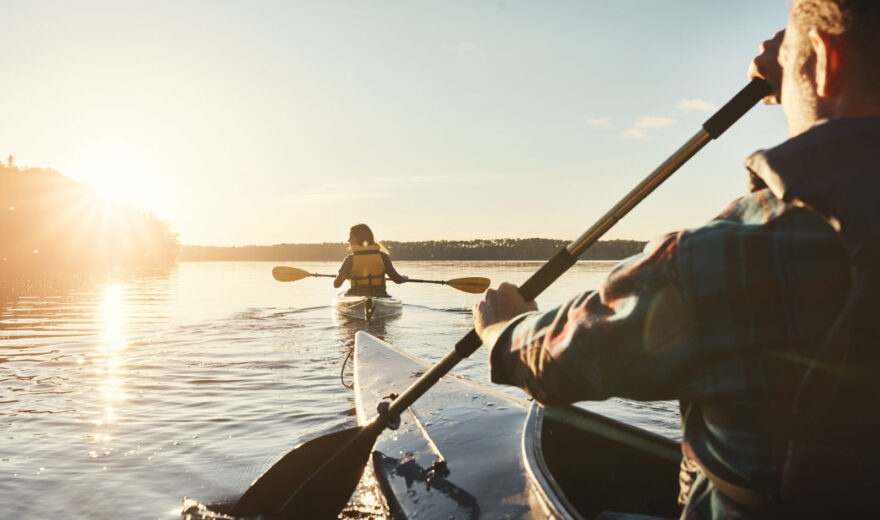Kaksi henkilöä melomassa ilta-auringossa