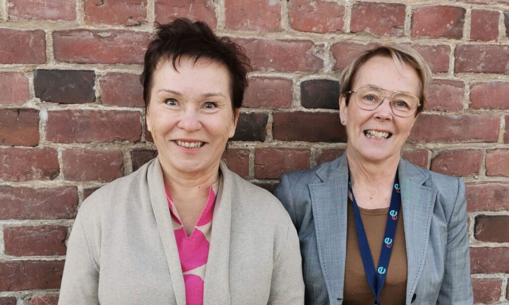 Helena ja Kirsi-Marja tiiliseinän edessä.