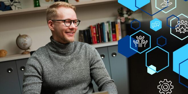 Nuorehko mieshenkilö istuu tietokoneen näytön ääressä ja hymyilee.